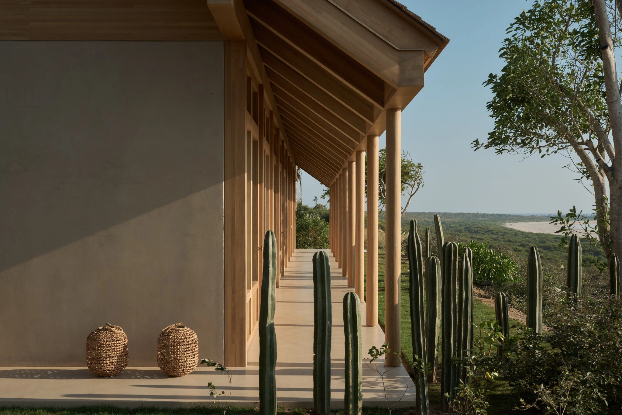 Timber colonnade opening onto cactus gardens and the coastal landscape