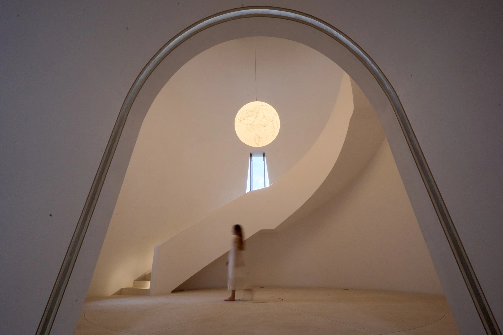 Sculptural staircase and arched architecture in warm natural light